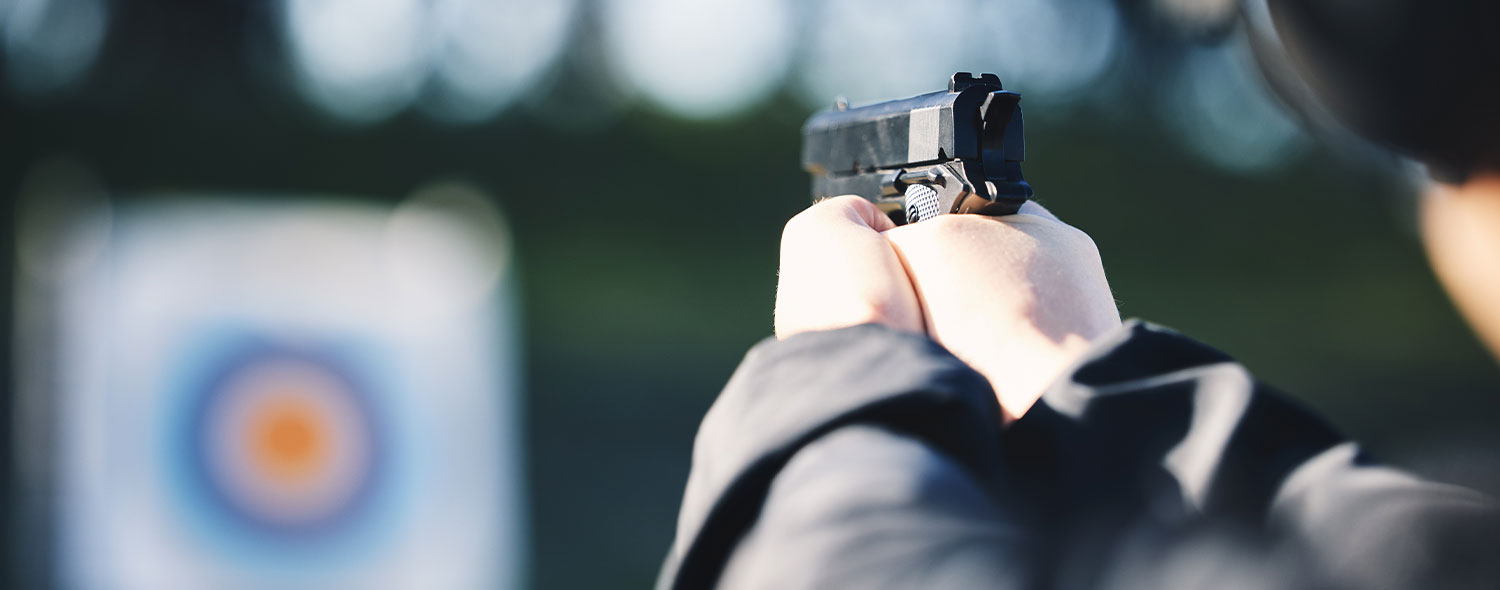 Someone firing a pistol at a target on a shooting range